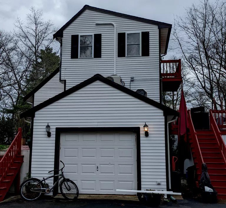 Detailed image of an intricate copper pipe system connected to a small gray expansion tank inside a residential mechanical room with a green wall.